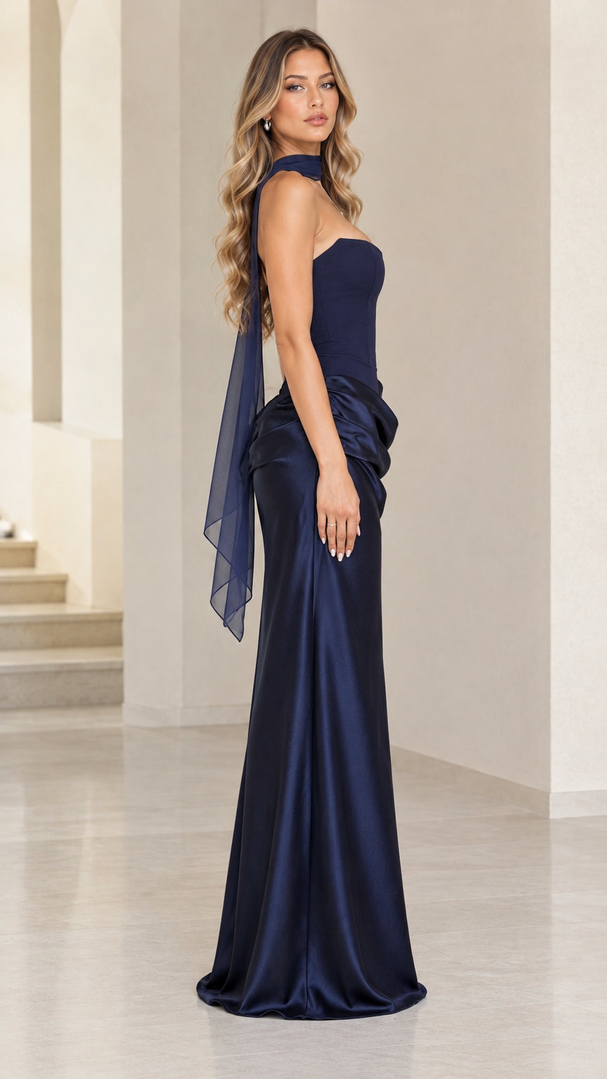 Side profile view of navy blue strapless draped satin maxi gown