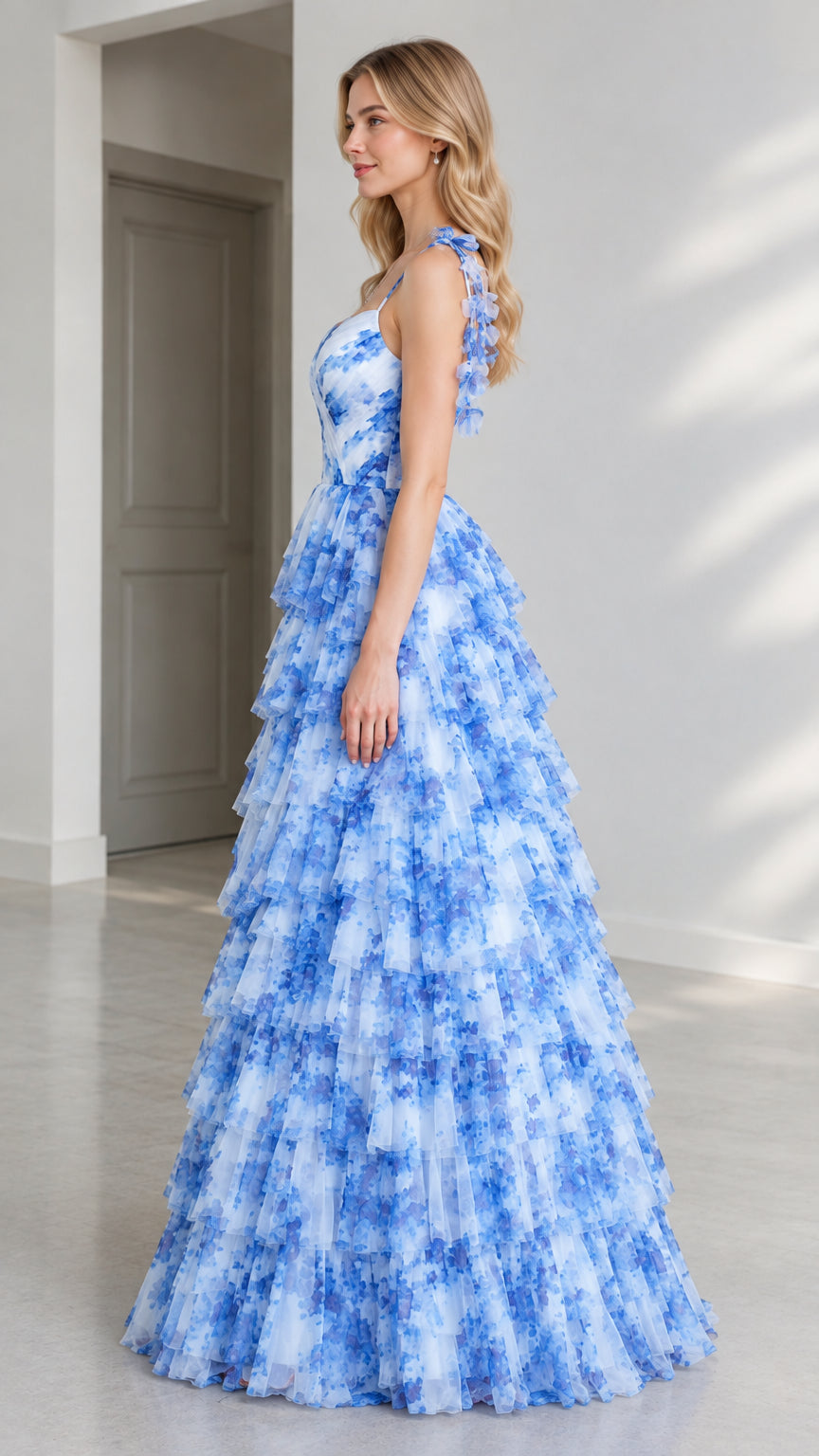 Side profile of model in full-length blue floral tiered tulle ball gown