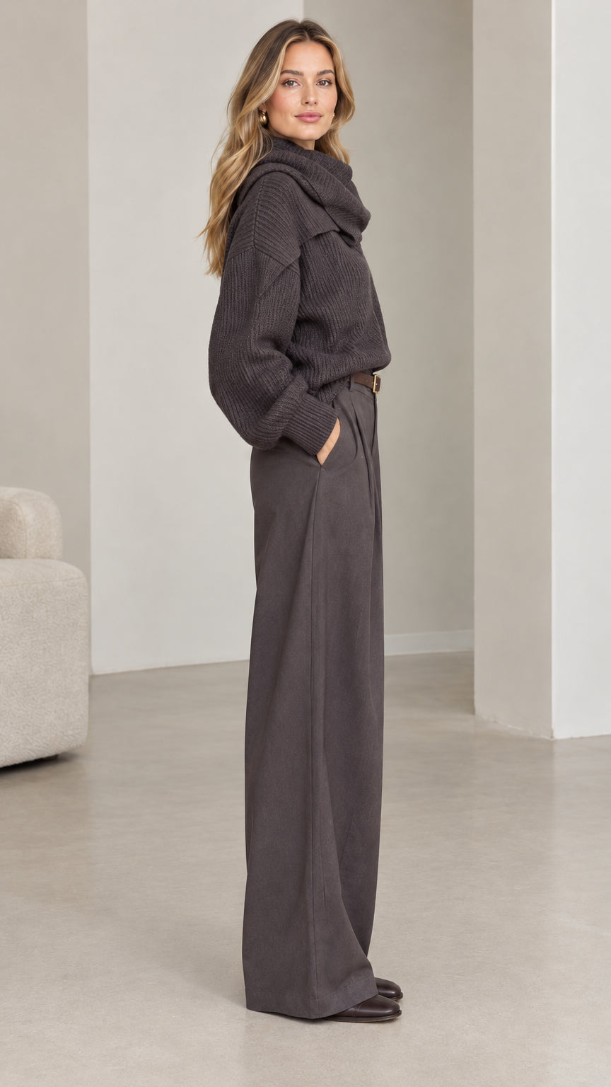 Side profile of model wearing dark grey ribbed knit draped neck sweater and wide-leg trousers