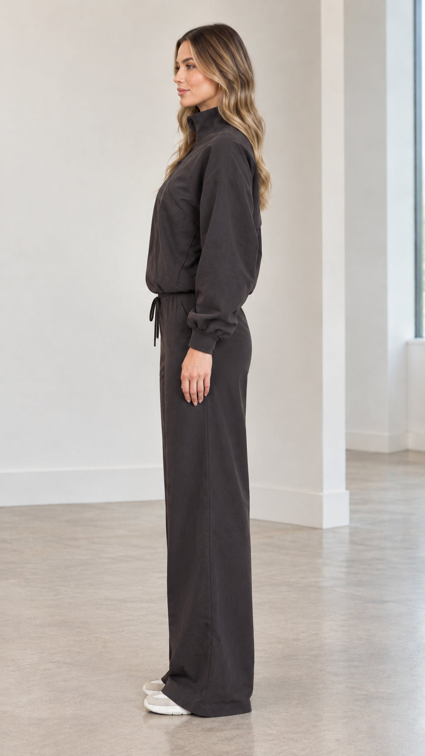 Side profile of woman wearing charcoal two-piece track jacket and wide-leg trousers