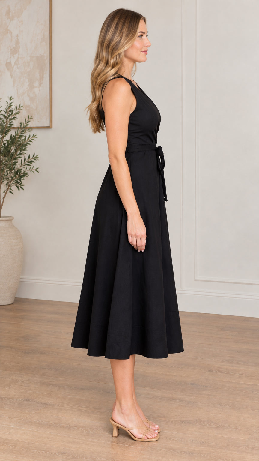 Side profile of model in black sleeveless A-line midi dress