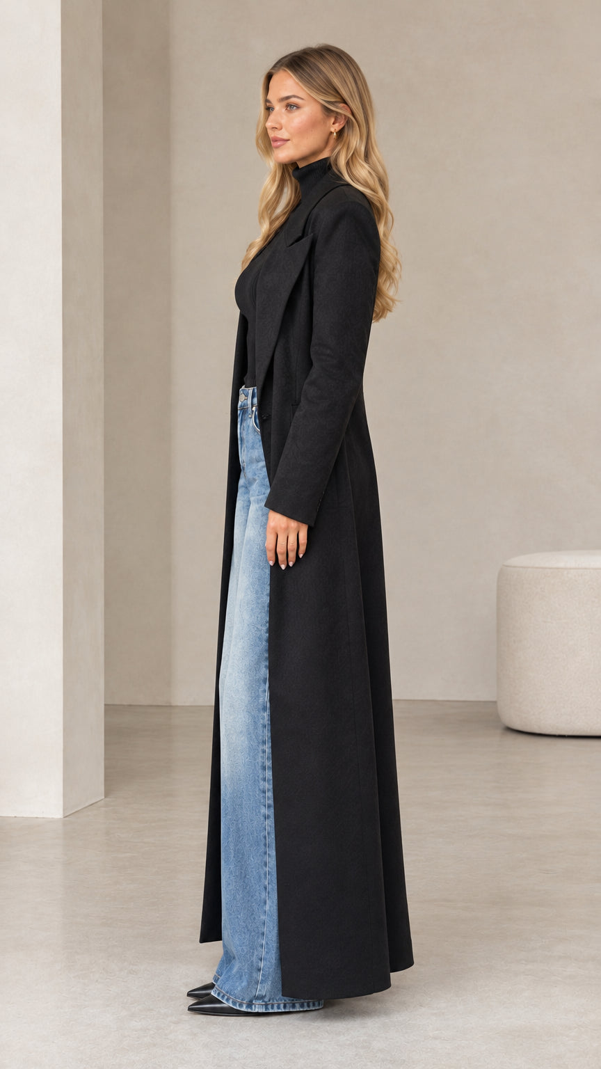 Side profile view of woman wearing black floor-length tailored maxi coat