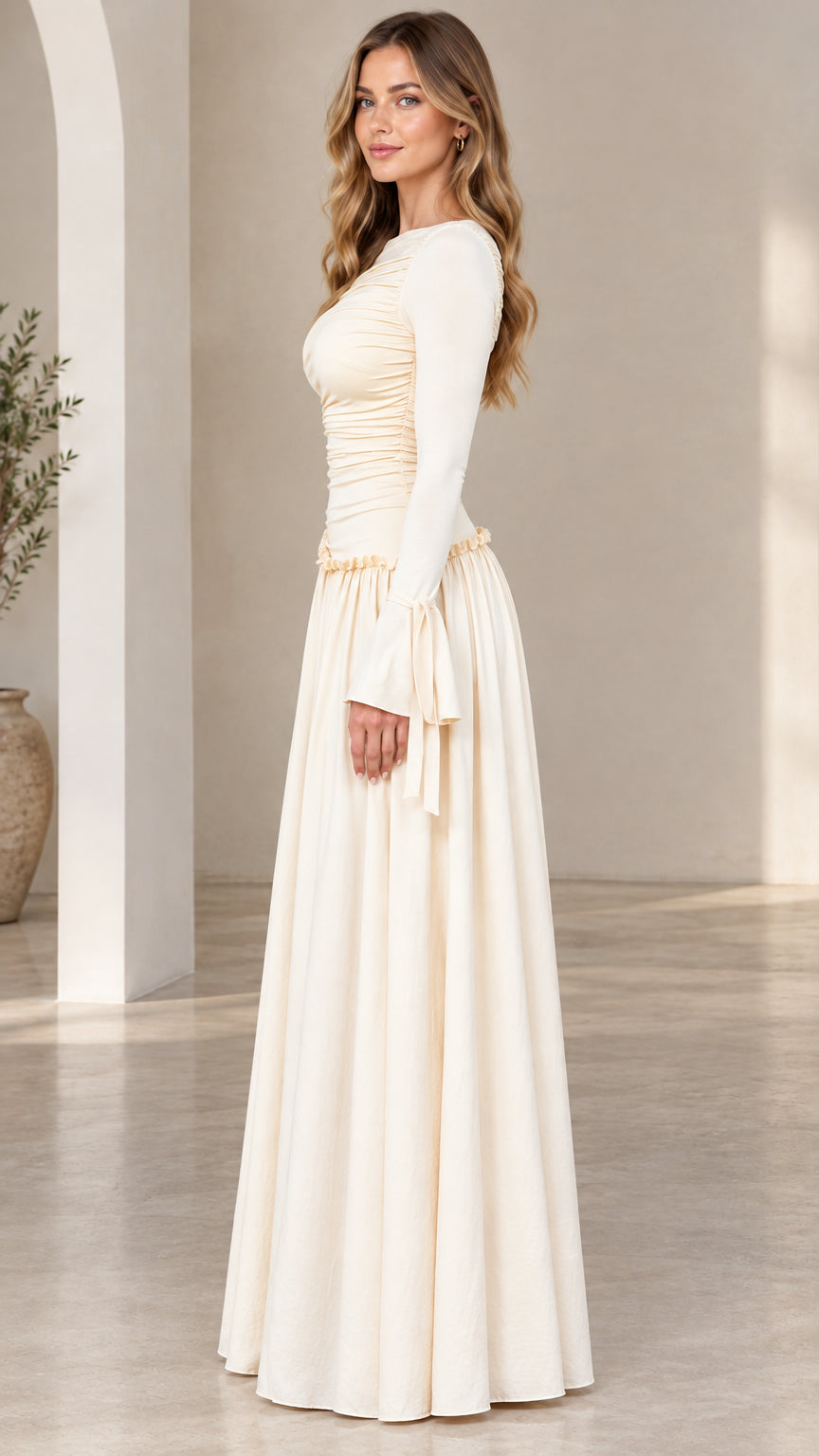 Side profile view of woman wearing cream long sleeve drop-waist maxi dress
