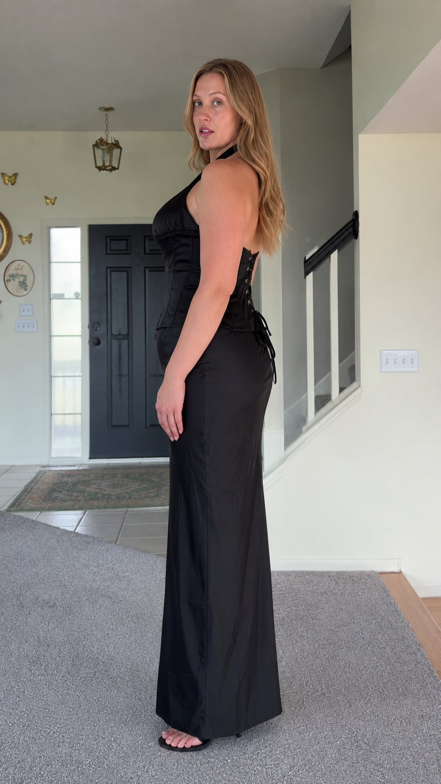 Side profile view of woman wearing black satin halter top and matching maxi skirt