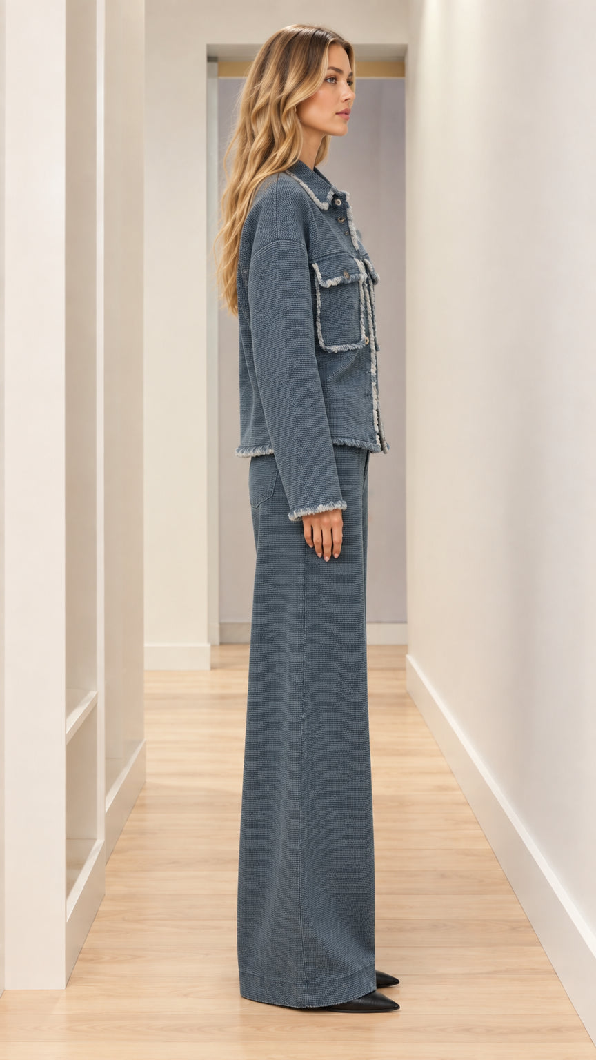Side profile view of woman wearing slate blue frayed edge jacket and coordinating wide leg pants