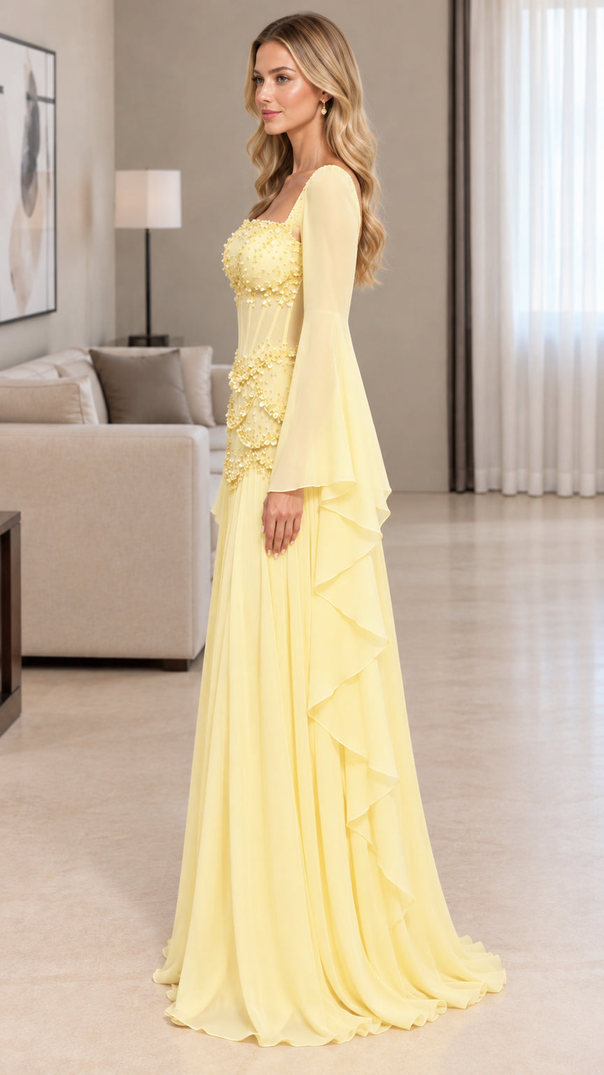 Side profile view of yellow beaded evening gown showing flowing cascading skirt and bell sleeves