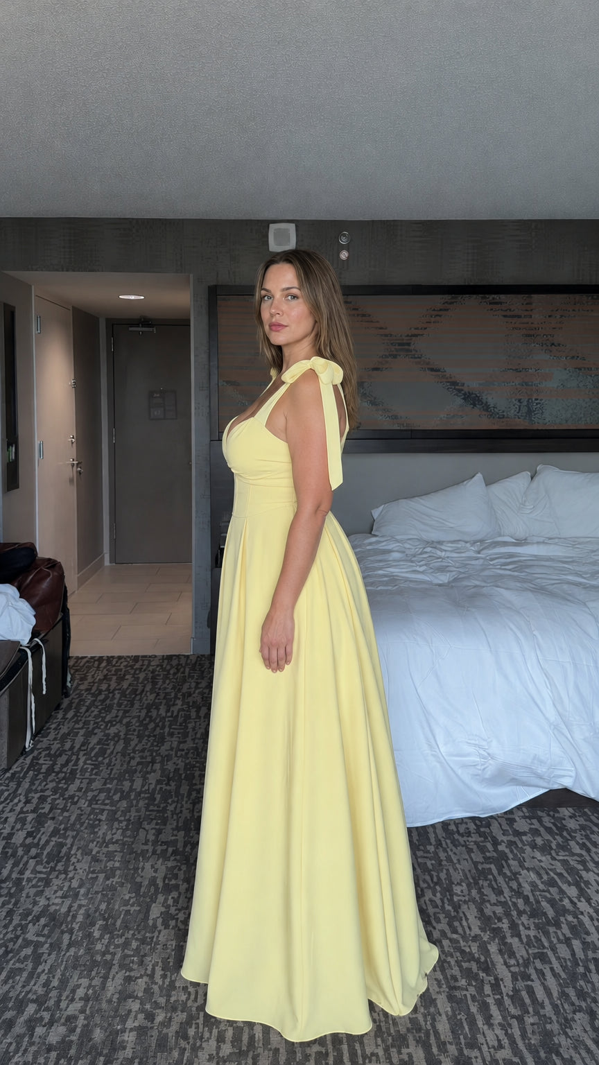 Side profile view of woman wearing yellow tie-shoulder A-line maxi dress