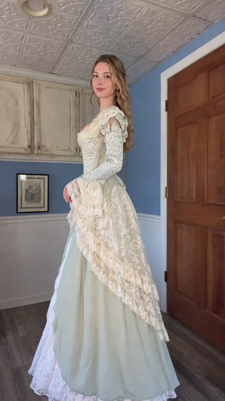 Side profile of woman in sage green Renaissance gown showing tiered lace overskirt