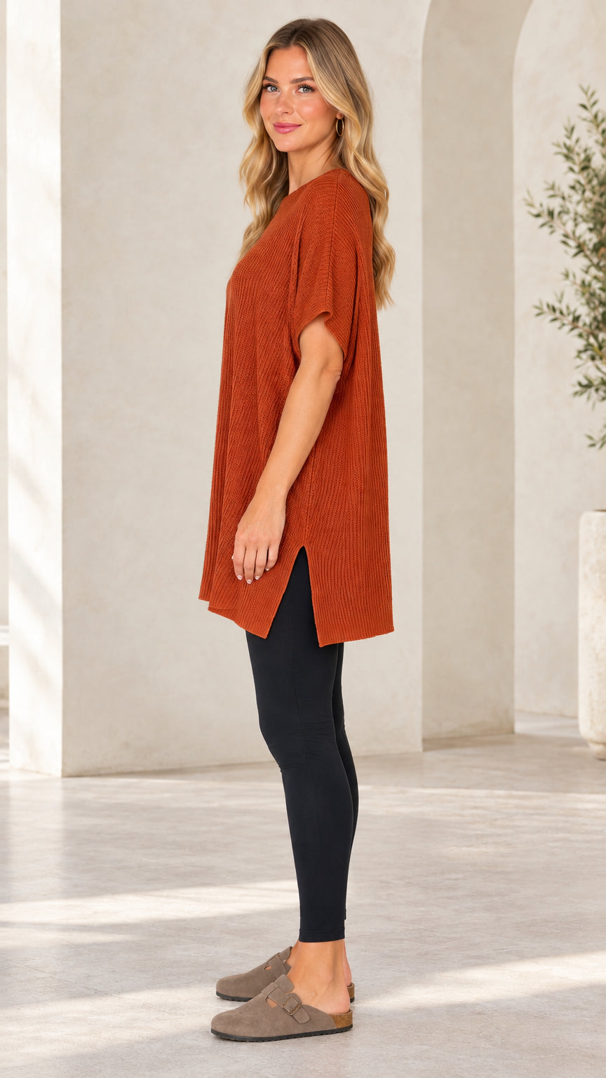 Side view of rust ribbed knit tunic sweater showing side slit detail
