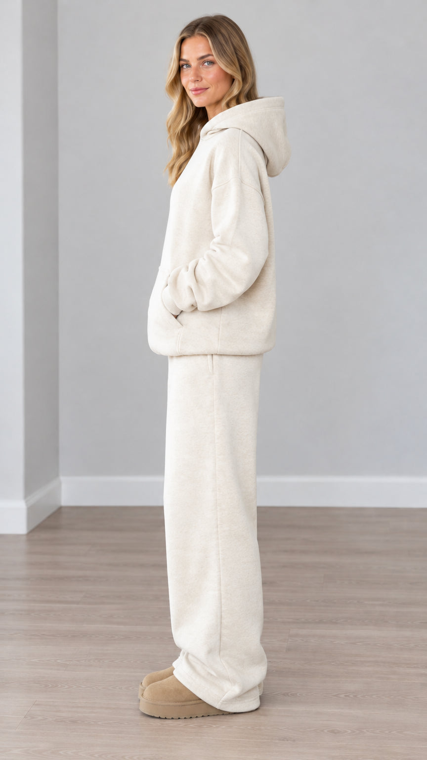 Side profile view of woman modeling cream two-piece fleece hoodie and pants set