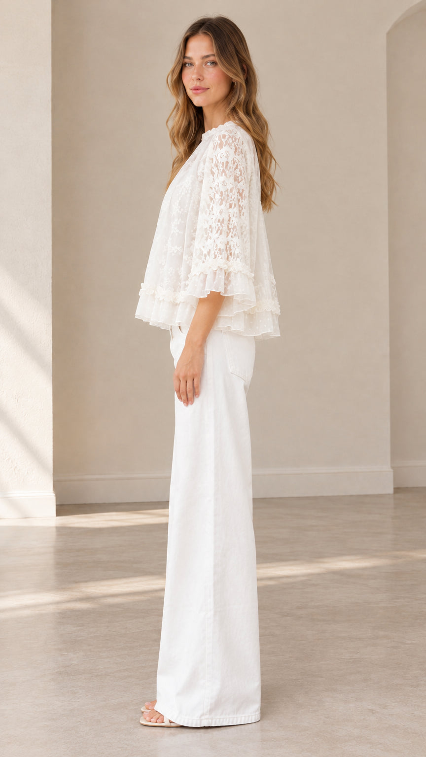 Side profile view of white floral lace blouse showcasing tiered hemline and relaxed drape