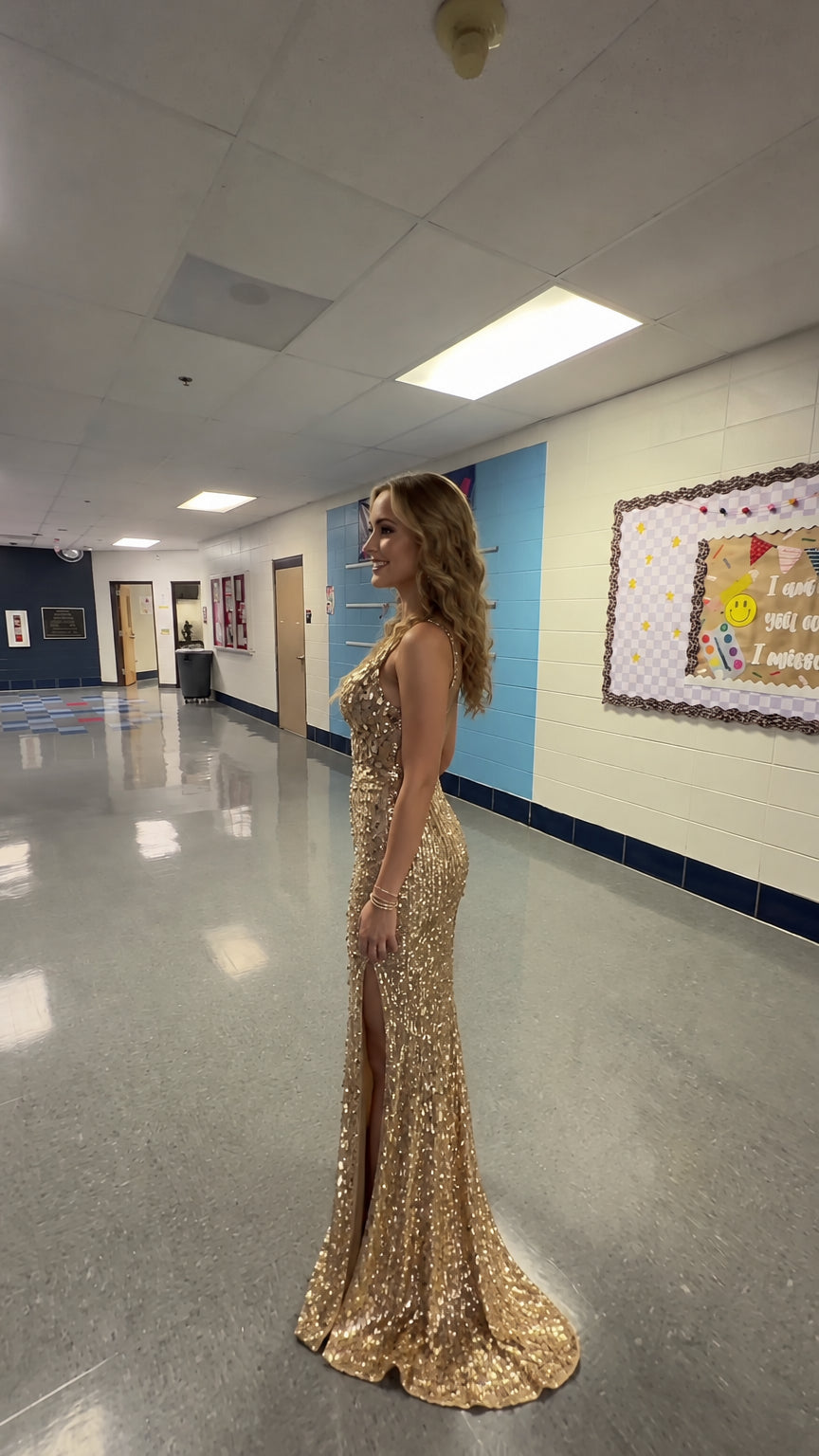 Side profile of woman in fitted gold sequin formal maxi dress