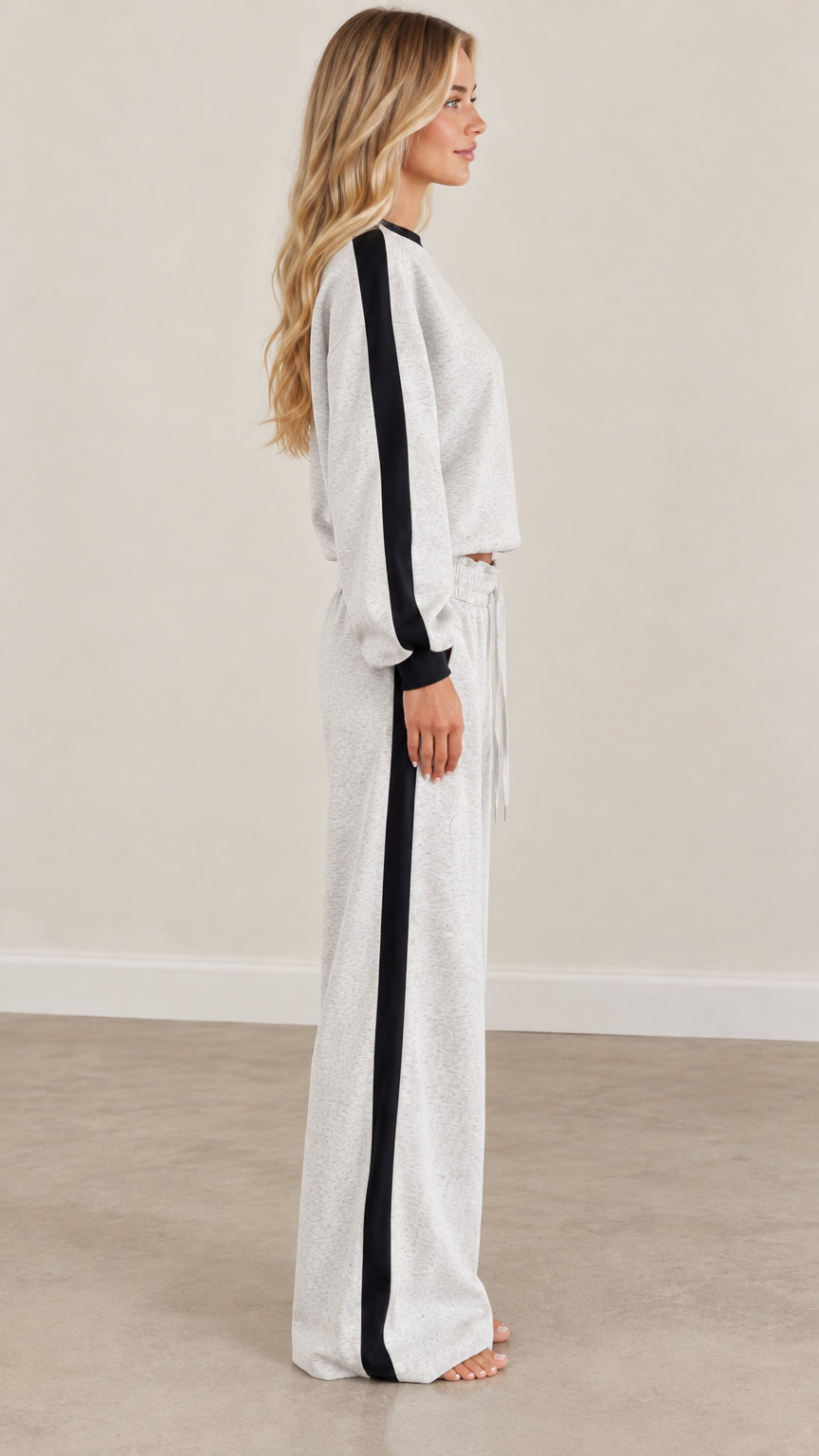 Side profile of model wearing heather gray sweatshirt and wide-leg pants set with contrast black stripe