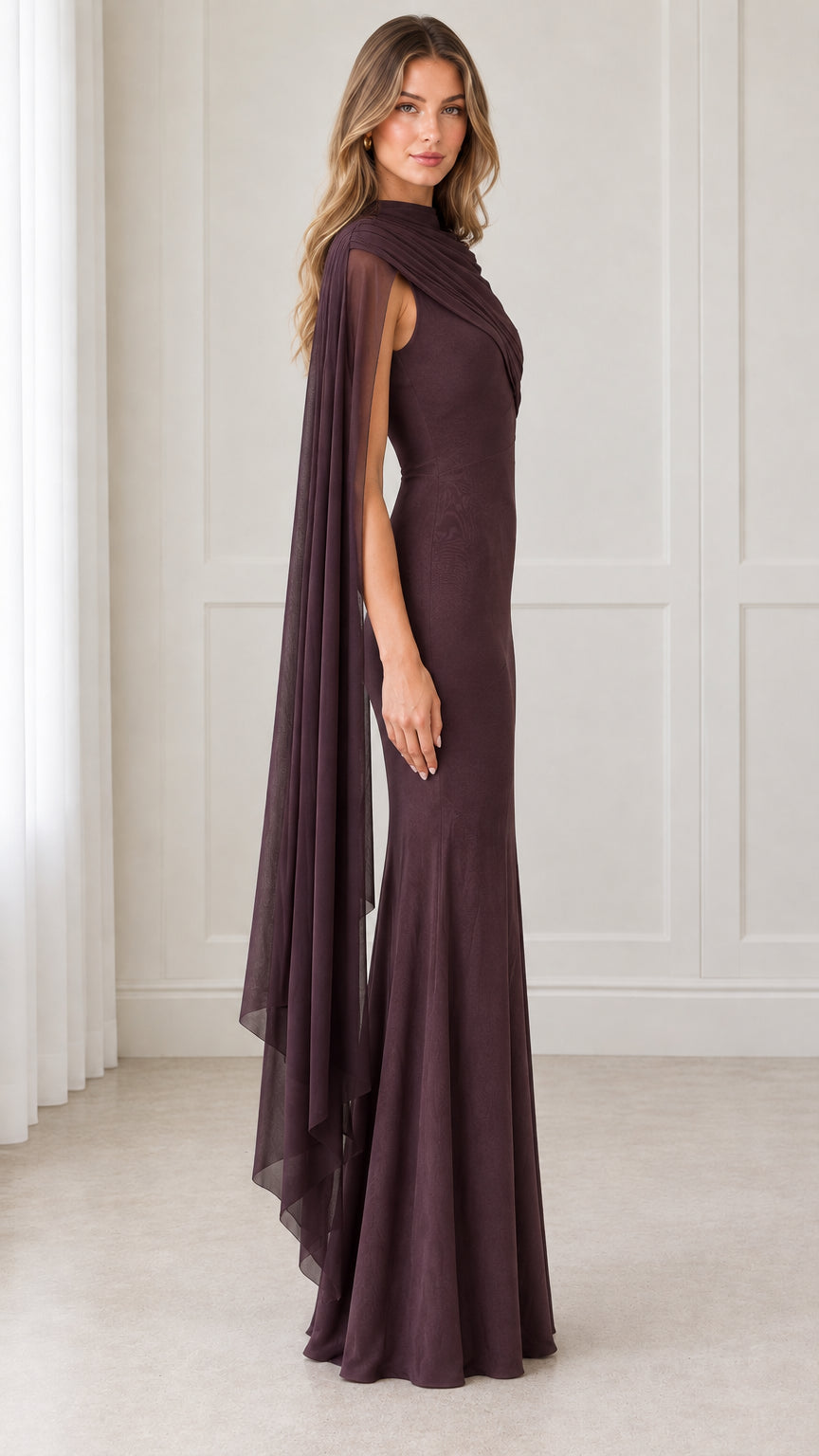 Side profile view of model in deep plum draped cape sleeve formal gown