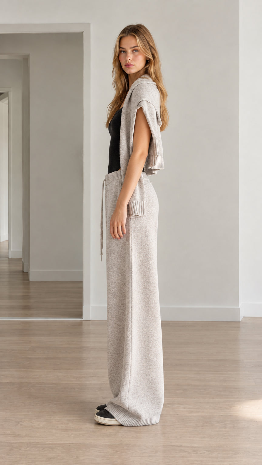 Side view of woman wearing heather gray knit hooded vest and wide-leg trousers