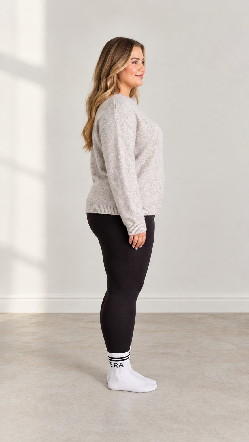 Side profile view of model wearing Light Grey knit pullover sweater