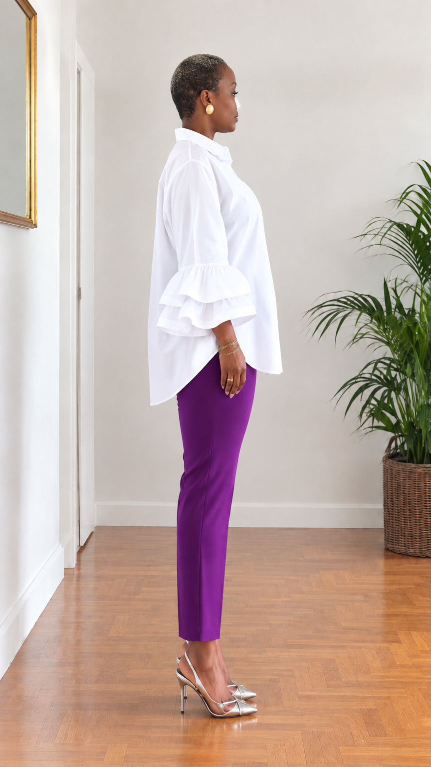 Side profile view of woman modeling white ruffle cuff button-down blouse with curved hem