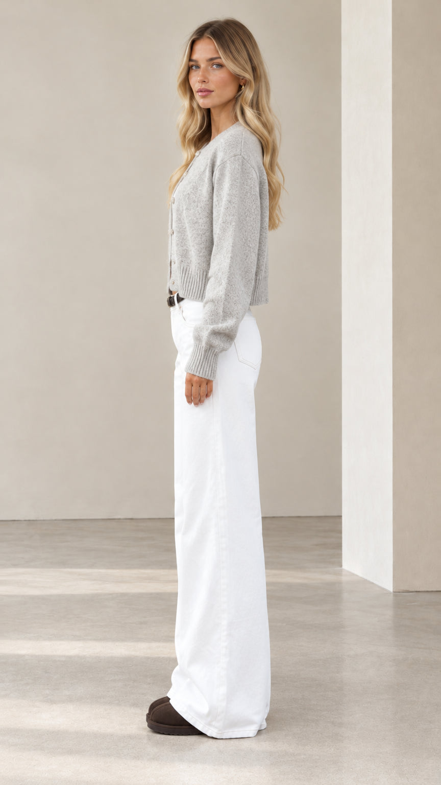 Side profile of model wearing a grey cropped buttoned knit cardigan
