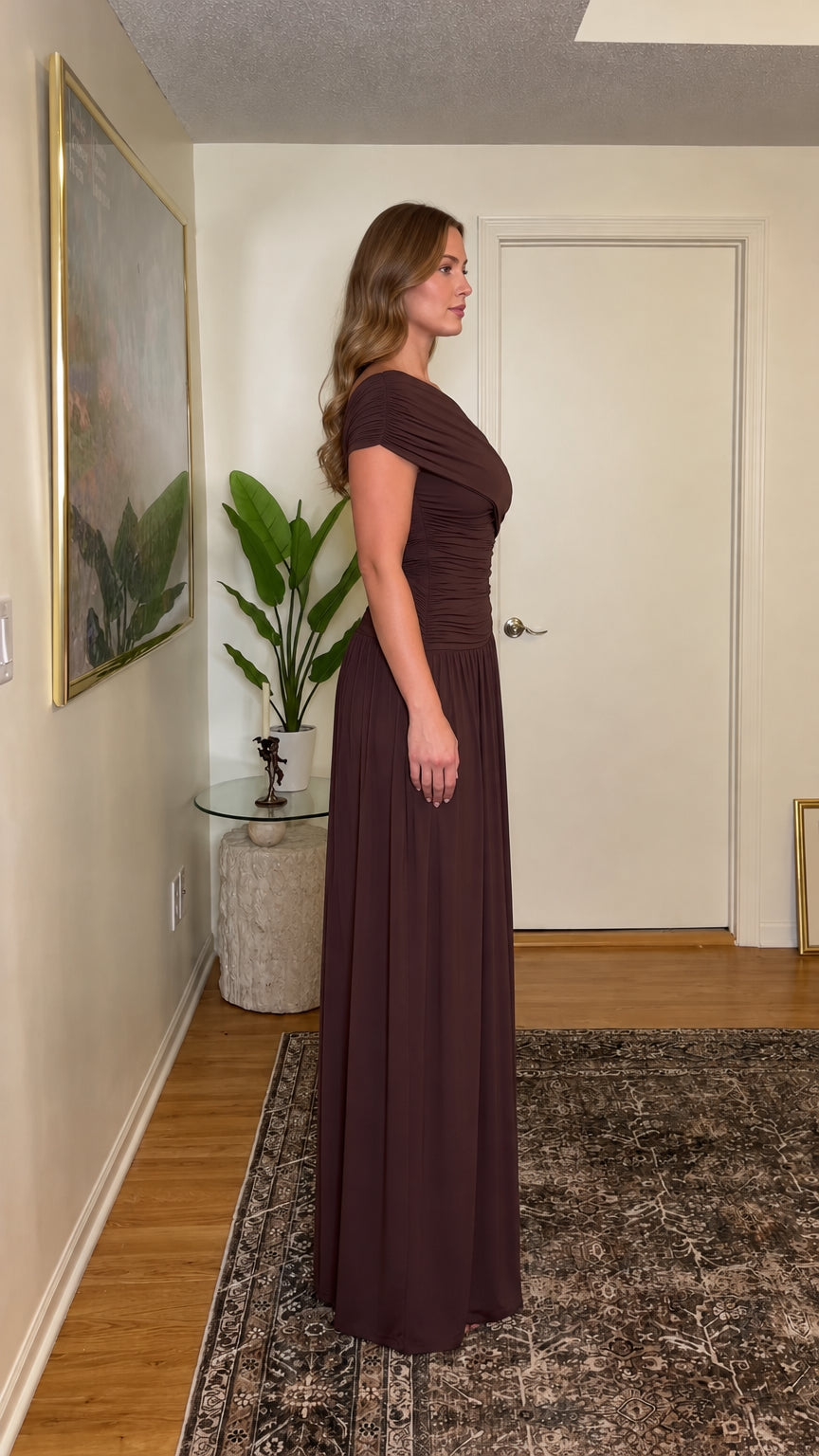 Side full-length profile of woman wearing chocolate brown one-shoulder ruched maxi dress