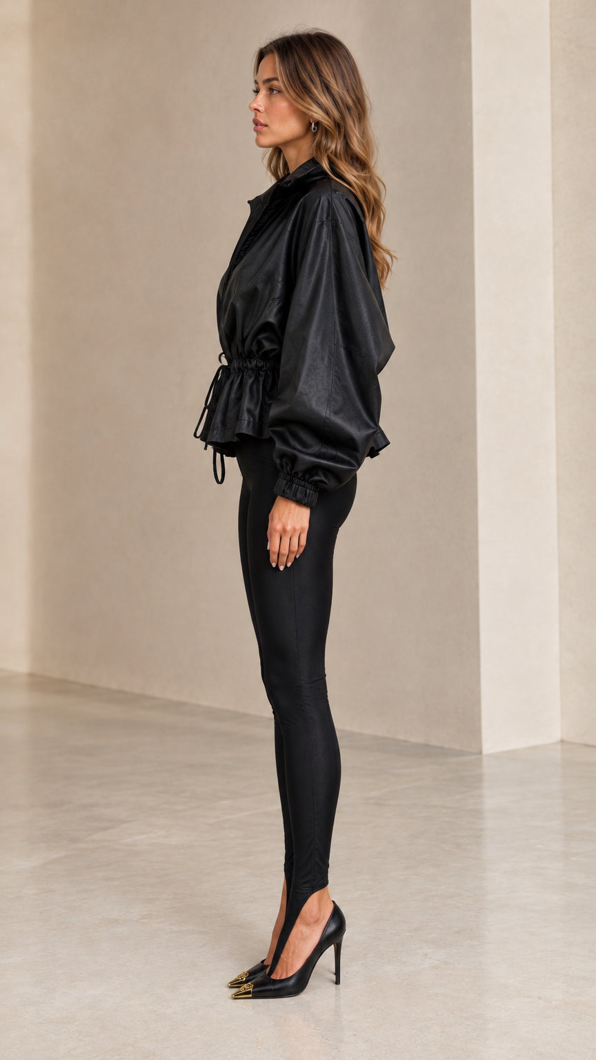 Side profile view of model wearing black drawstring peplum jacket