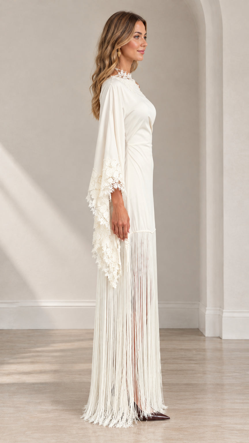 Side profile of woman in ivory long-sleeve fringe evening gown