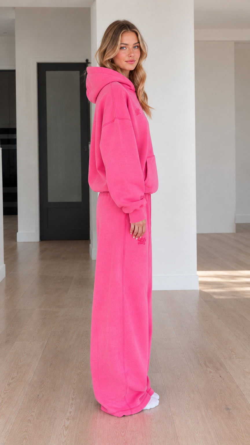 Side profile view of model wearing Fuchsia two-piece hoodie and sweatpants set