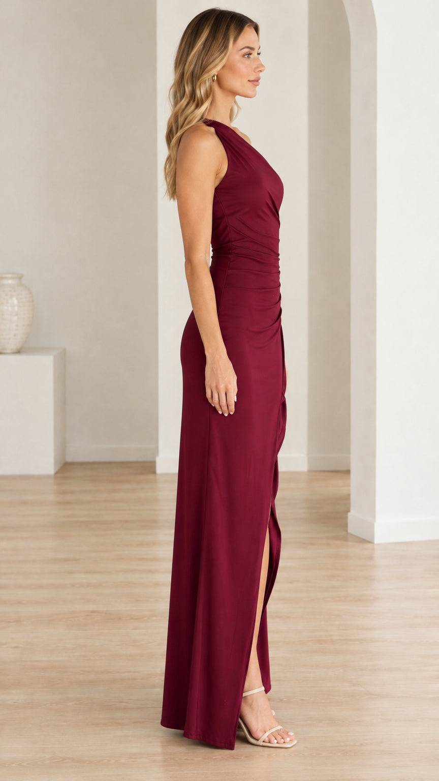 Side profile view of woman wearing burgundy one-shoulder evening maxi dress