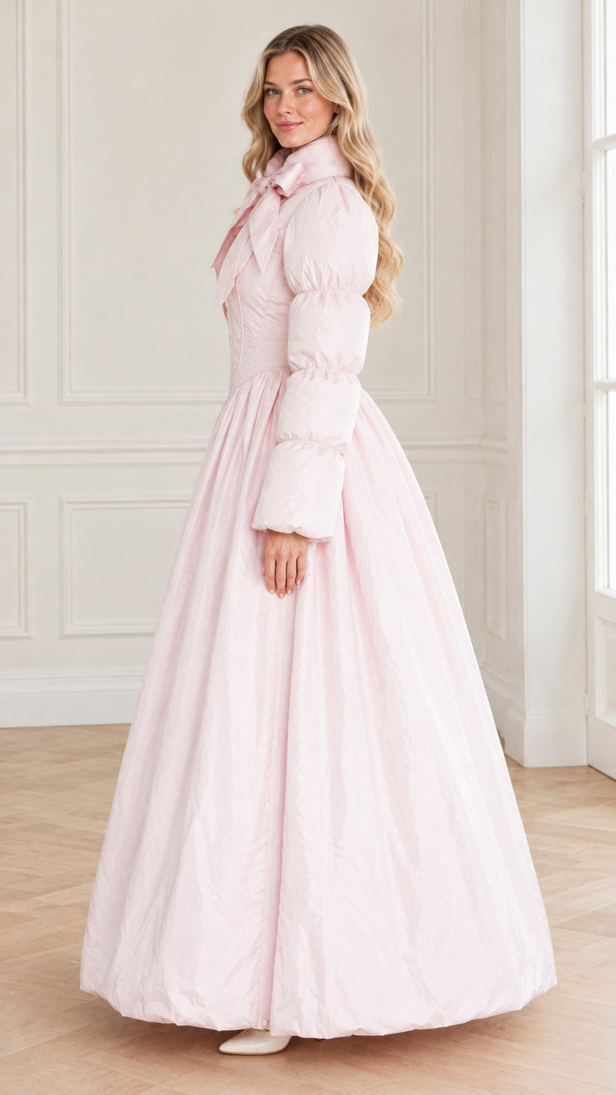 Side angle view of model wearing the light pink dramatic flared maxi puffer coat