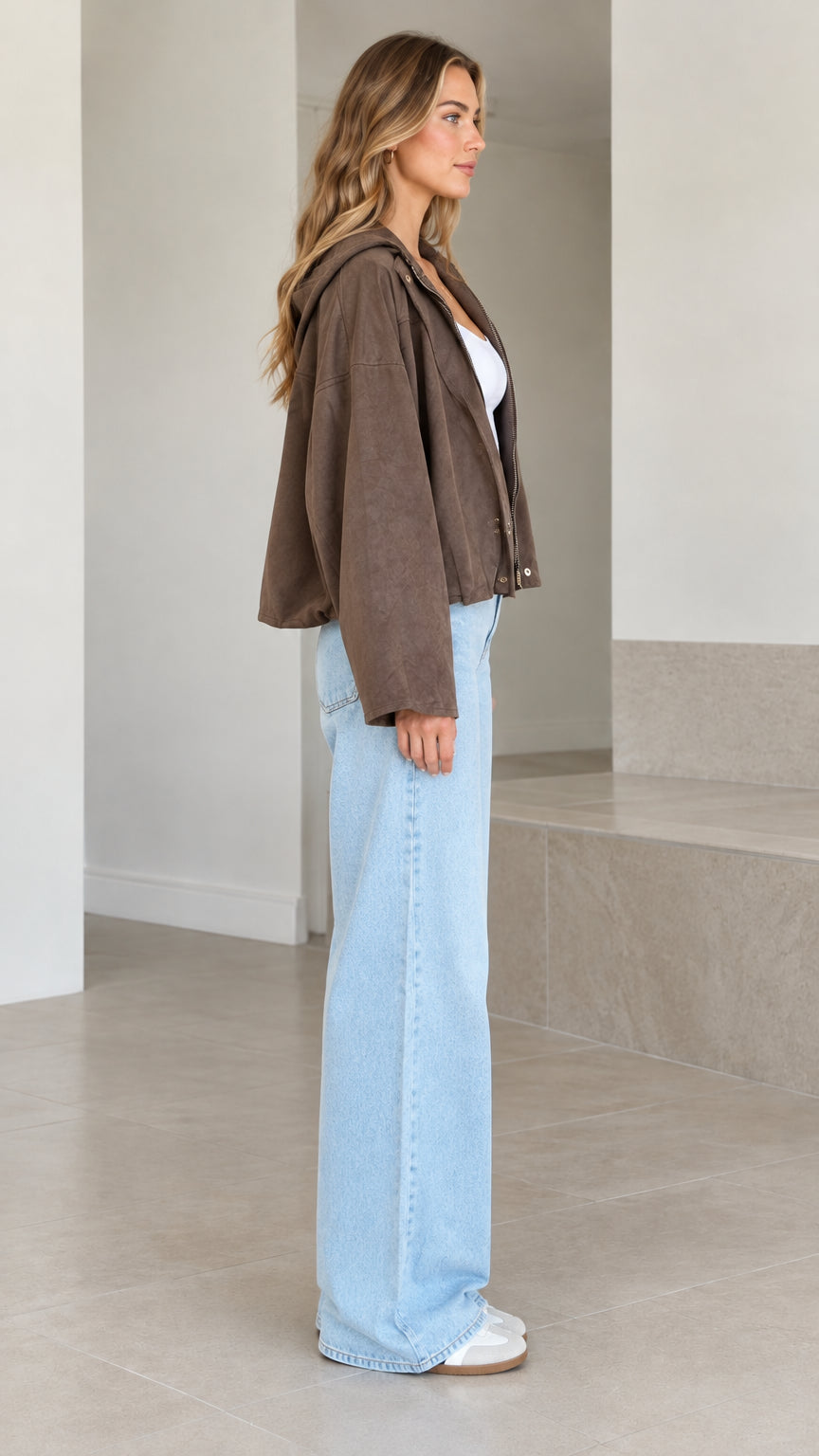 Side profile of brown relaxed hooded cropped jacket showing loose wide-sleeve cut