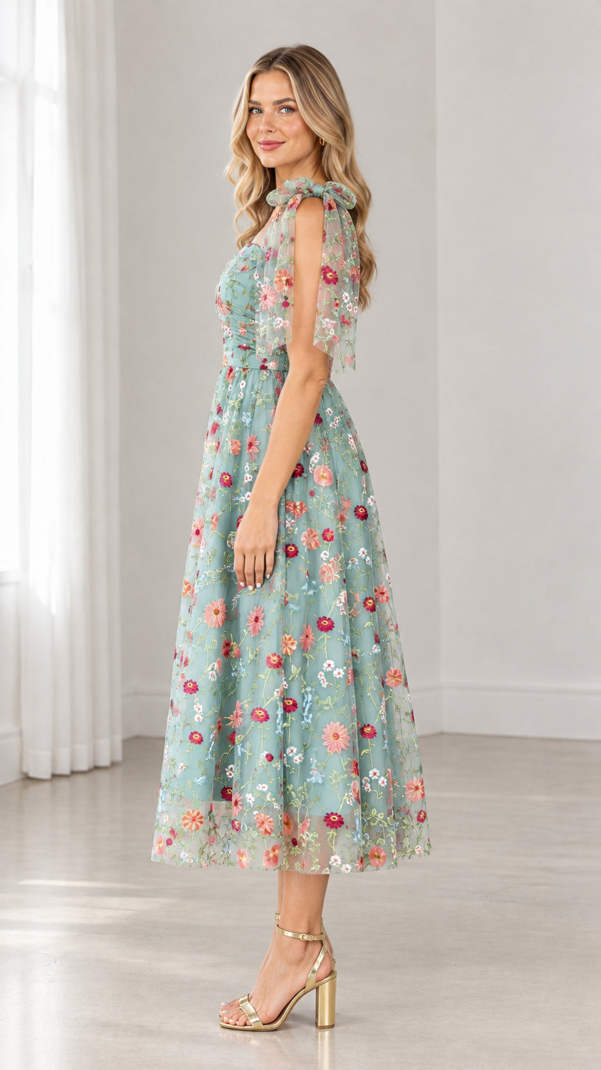 Side profile of model in sage green embroidered tulle midi dress with flutter tie straps
