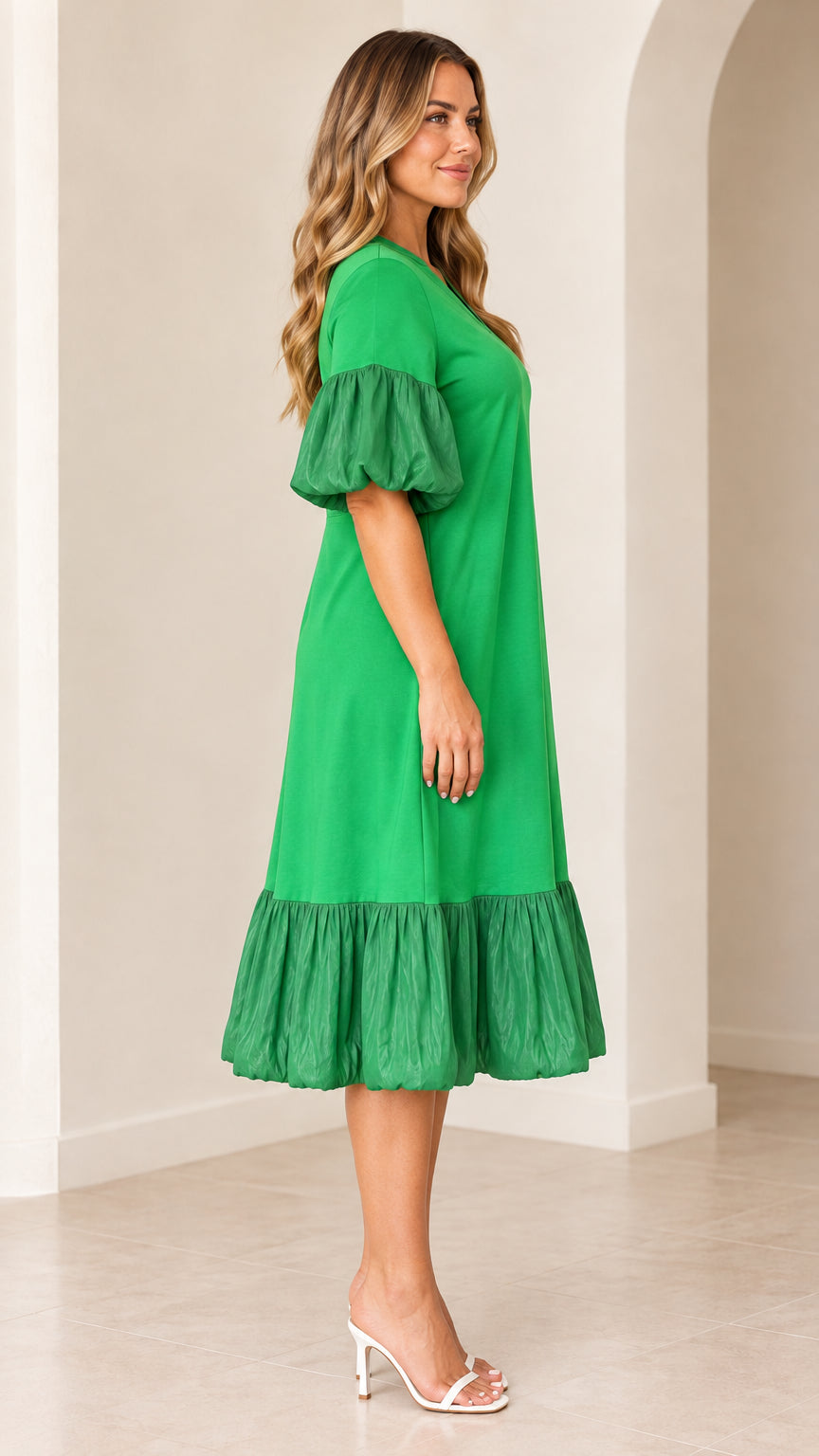 Side angle view of model in green ruffle-hem midi dress