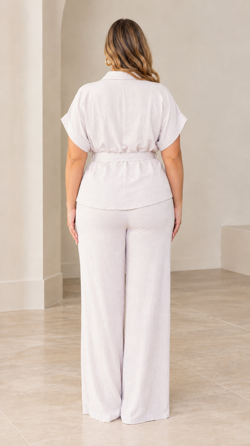 Back full view of woman wearing light grey collared top and wide leg pants