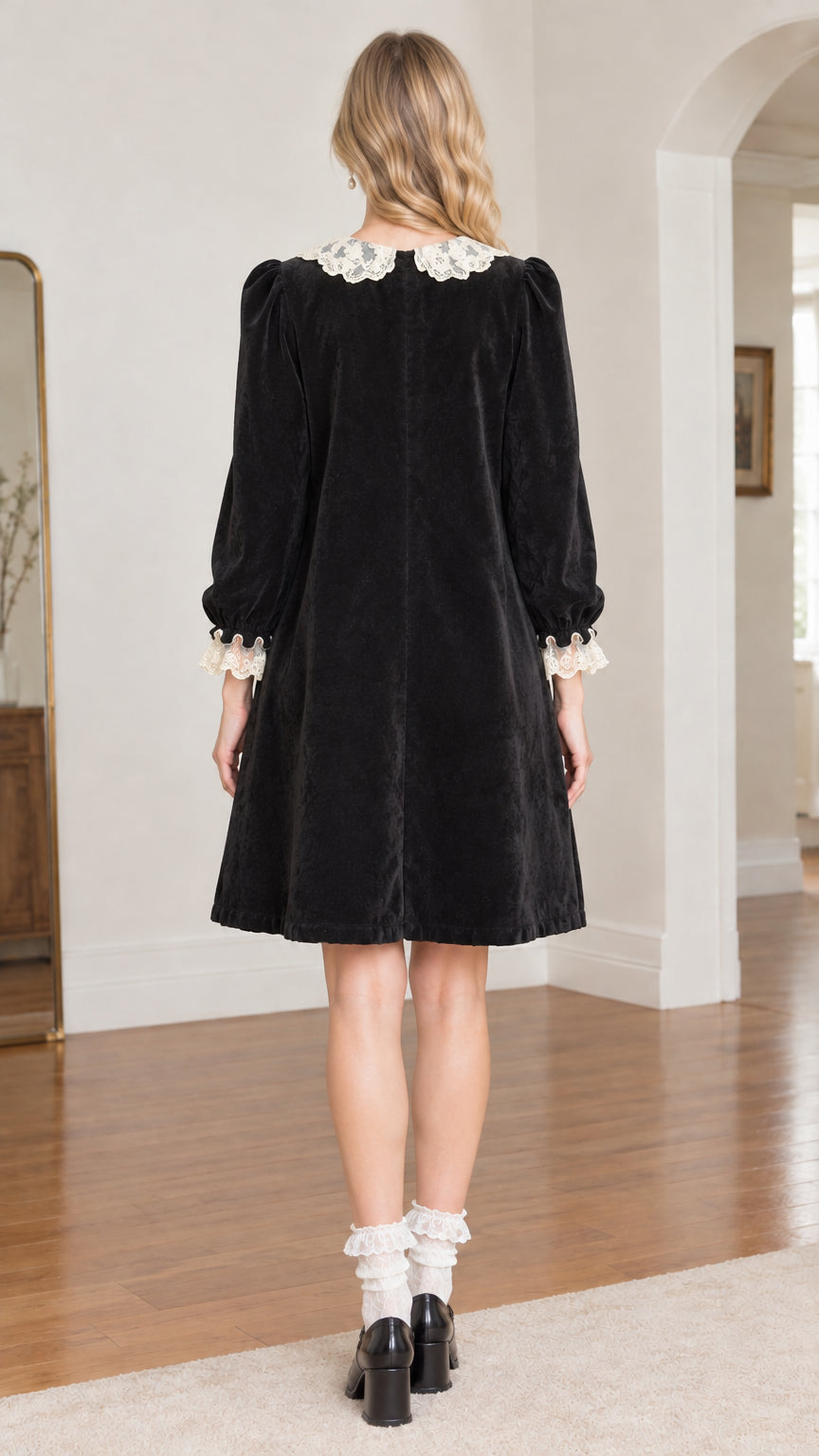 Back view of model wearing black velvet knee-length dress with lace Peter Pan collar