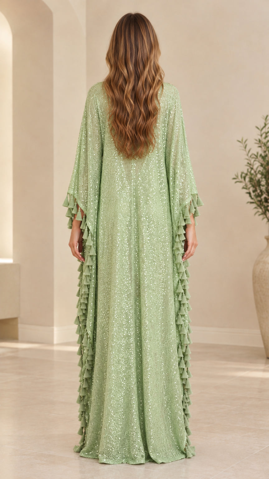 Back view of woman wearing sage green sequin kaftan gown with tassel fringe edges