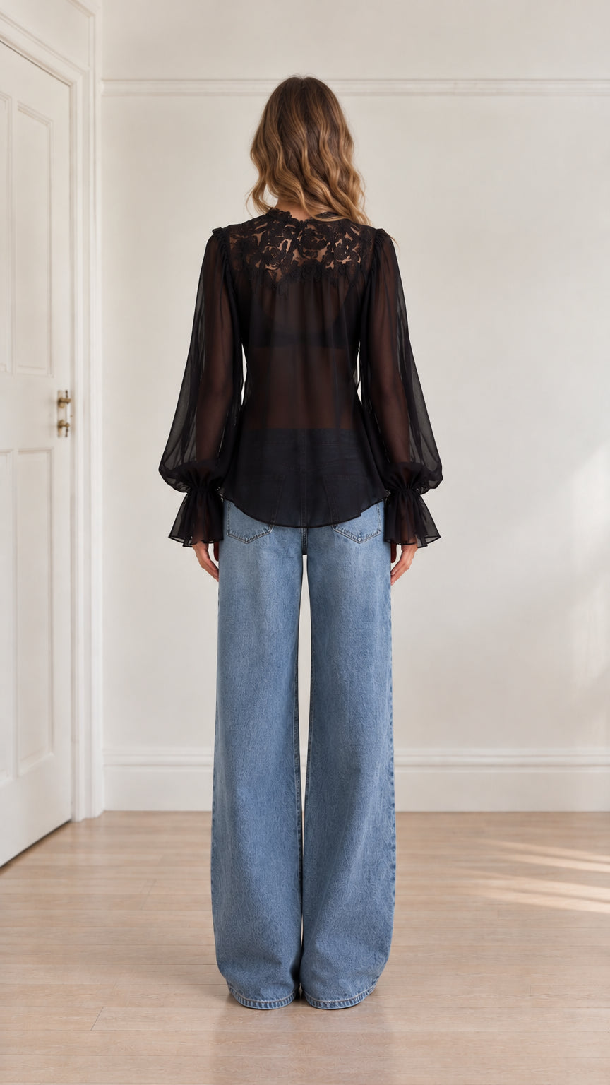 Back view of model wearing black sheer lace blouse showing intricate back lace detailing