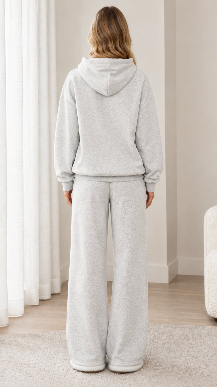 Back full-length view of woman wearing light heather grey pullover hoodie and wide-leg sweatpants