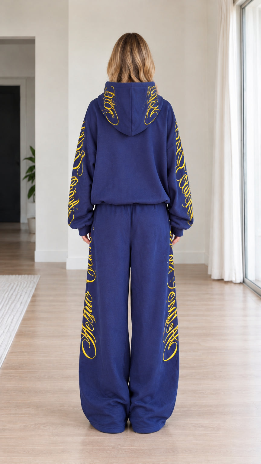 Back view of woman wearing royal blue hooded sweatshirt and wide-leg sweatpants set with hood embroidery