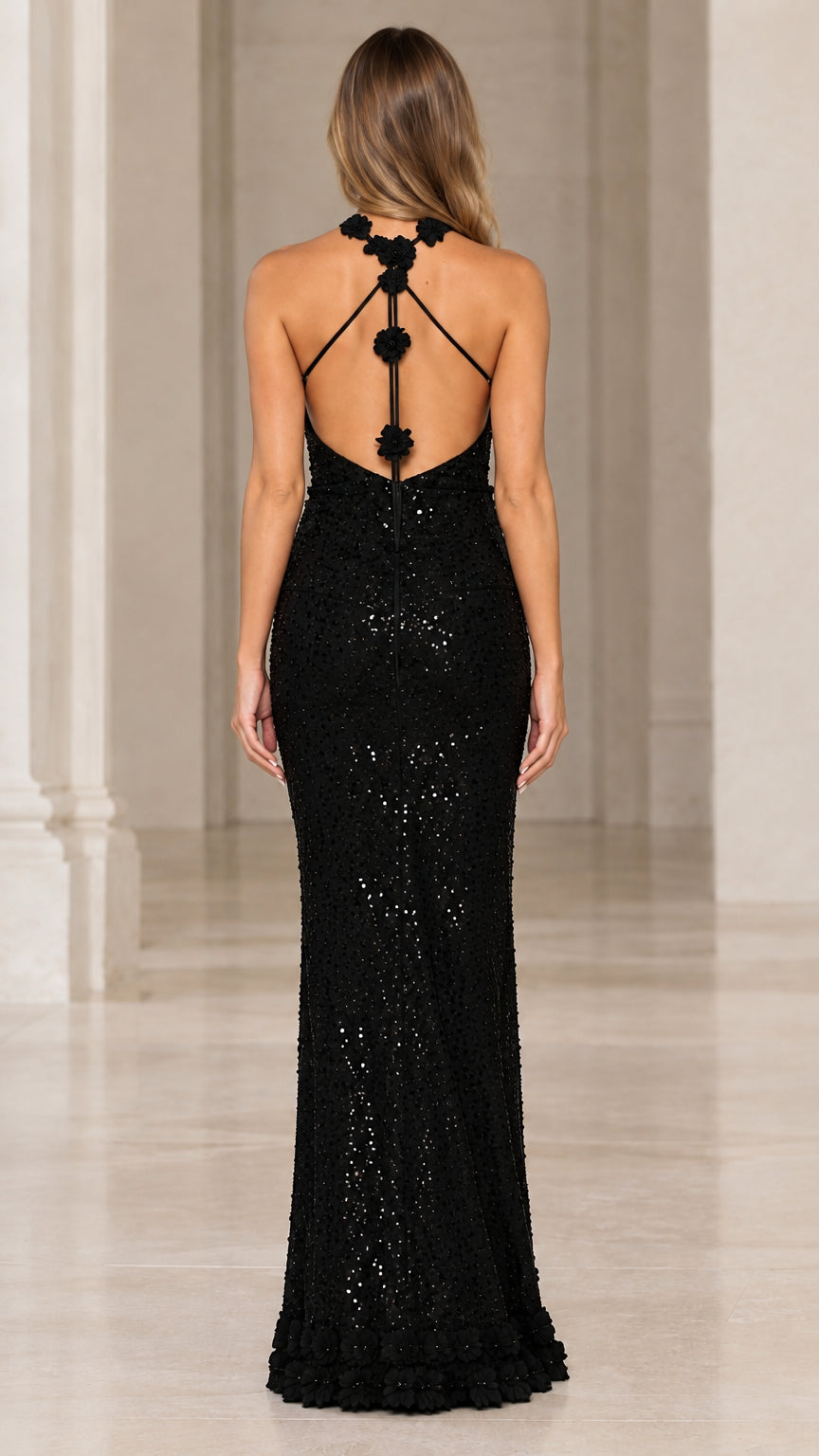 Back view of model wearing black sequin gown with strappy floral rosette back