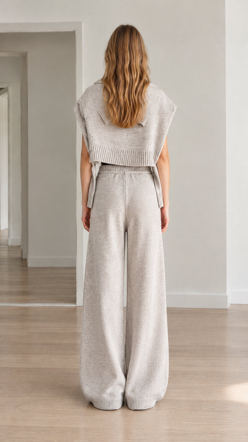 Back view of woman wearing heather gray knit cropped hooded vest and matching knit pants