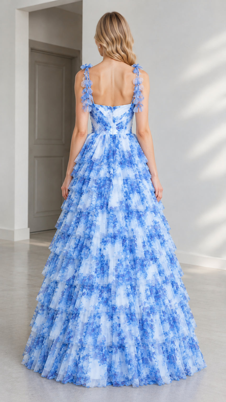 Back view of model showcasing floral shoulder straps and tiered skirt in blue