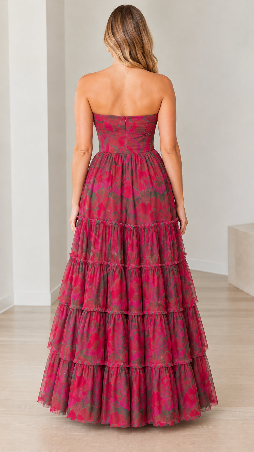 Back view of model in magenta floral strapless tiered evening maxi gown