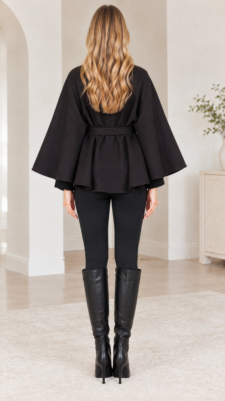 Back view of woman wearing black flared cape coat with tie waist