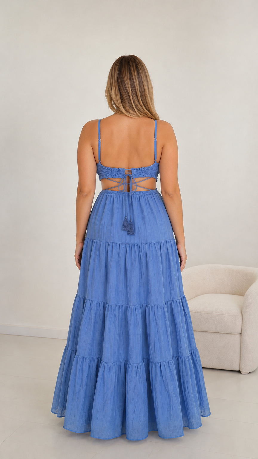 Back view of model in blue cutout maxi dress highlighting lace-up tie with tassels