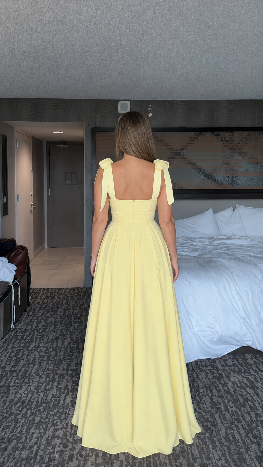 Back view of woman wearing yellow tie-shoulder evening maxi dress
