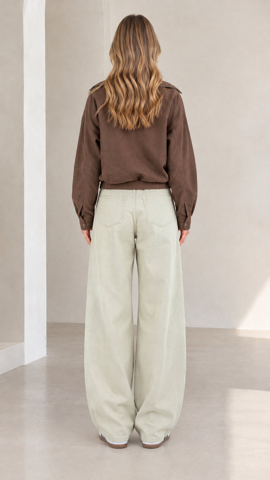 Back view of woman wearing brown utility jacket and wide-leg trousers