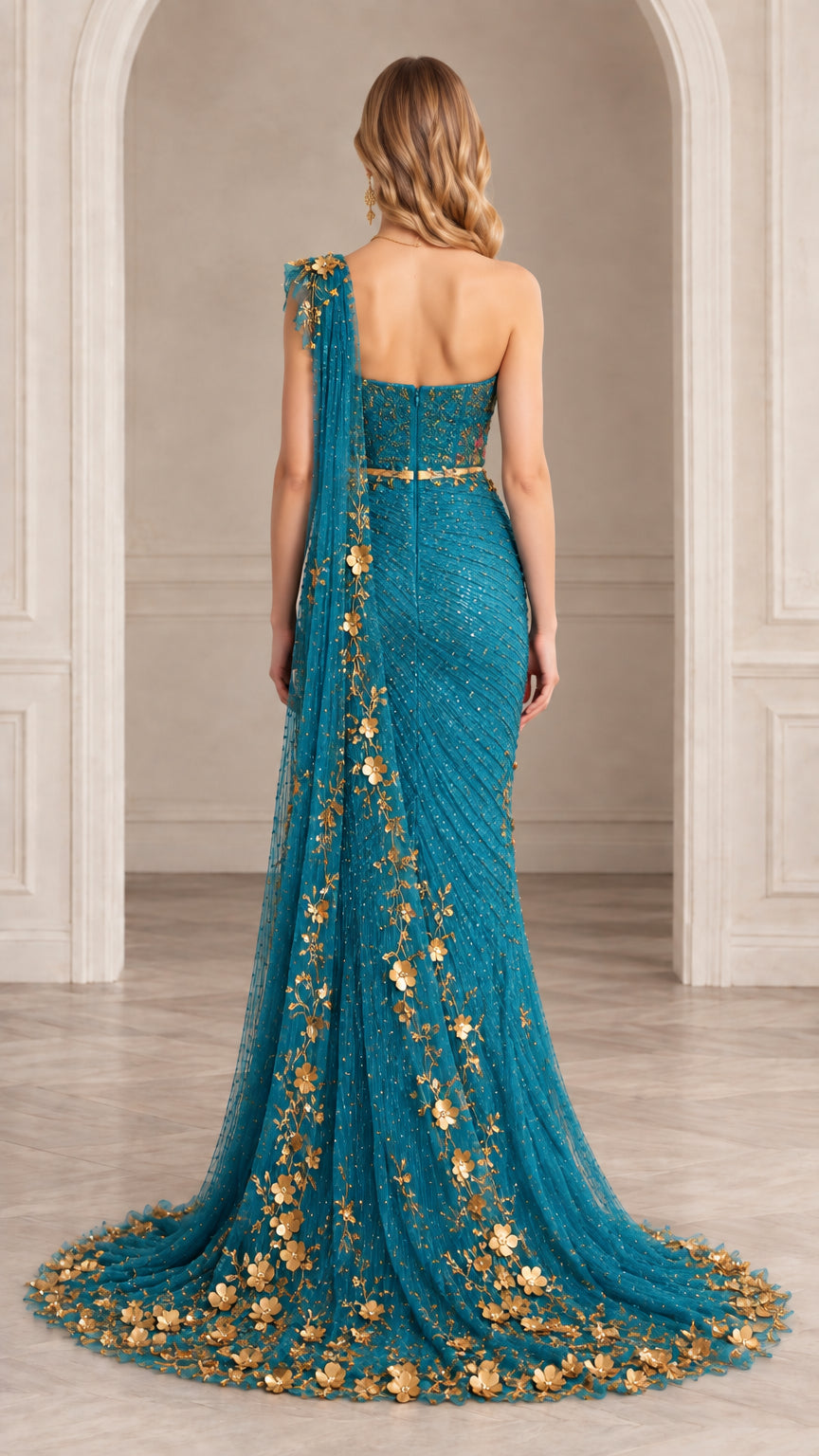 Back view of teal one-shoulder evening gown showcasing long trailing hem with gold flowers