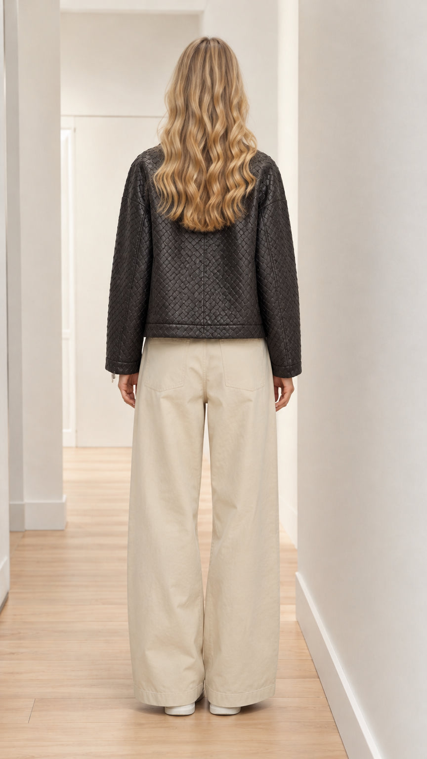 Back view of model showing clean drape of black woven zip jacket