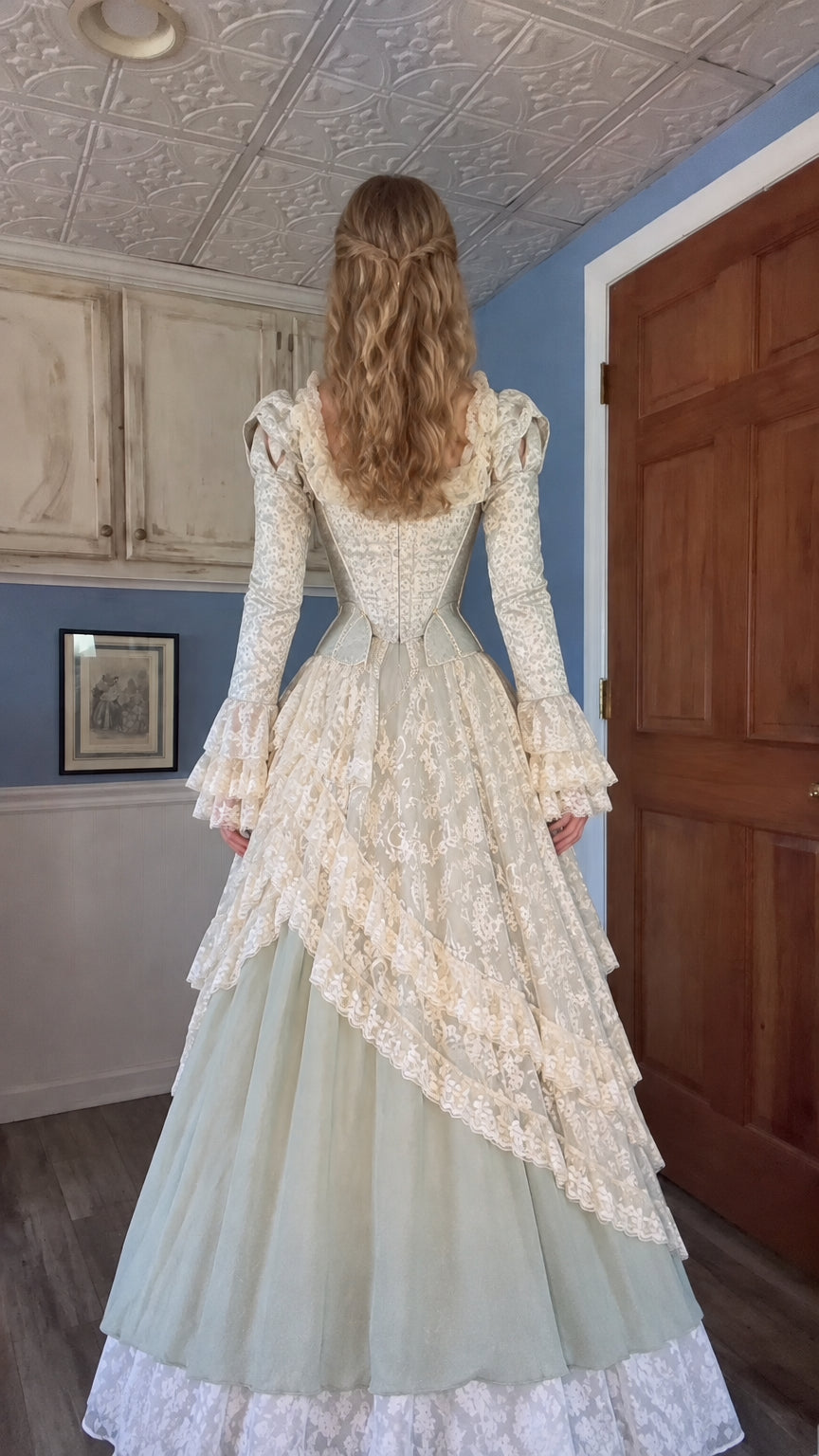 Back view of woman wearing sage green and cream lace Victorian ball gown