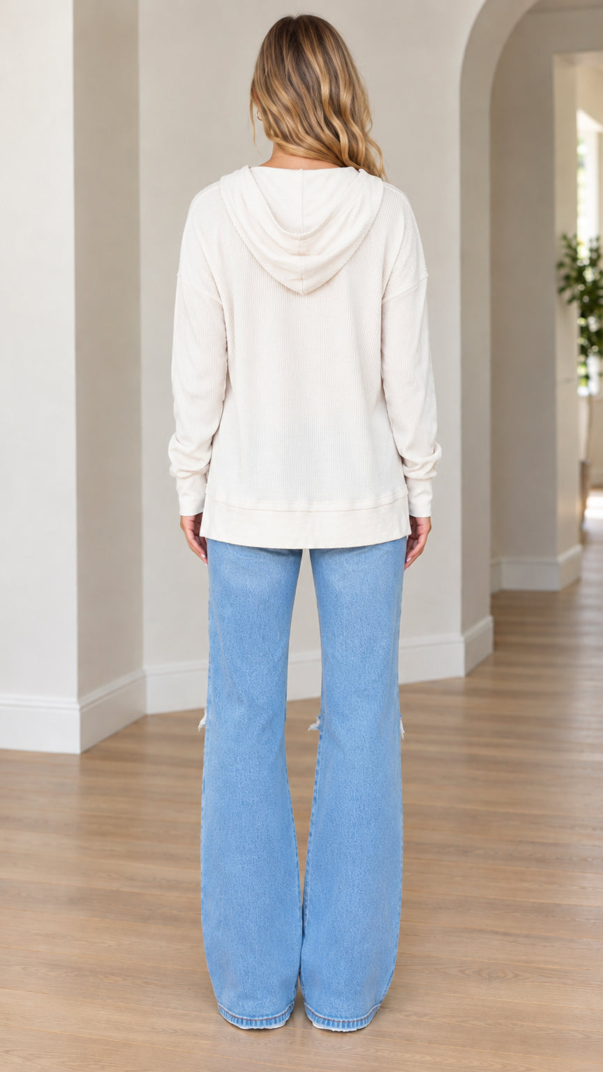 Back full-length view of model wearing cream hoodie showing hood detail and relaxed hem
