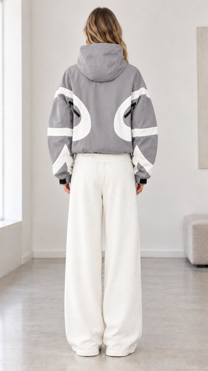 Rear view of model wearing grey hooded jacket with white curved back panel details